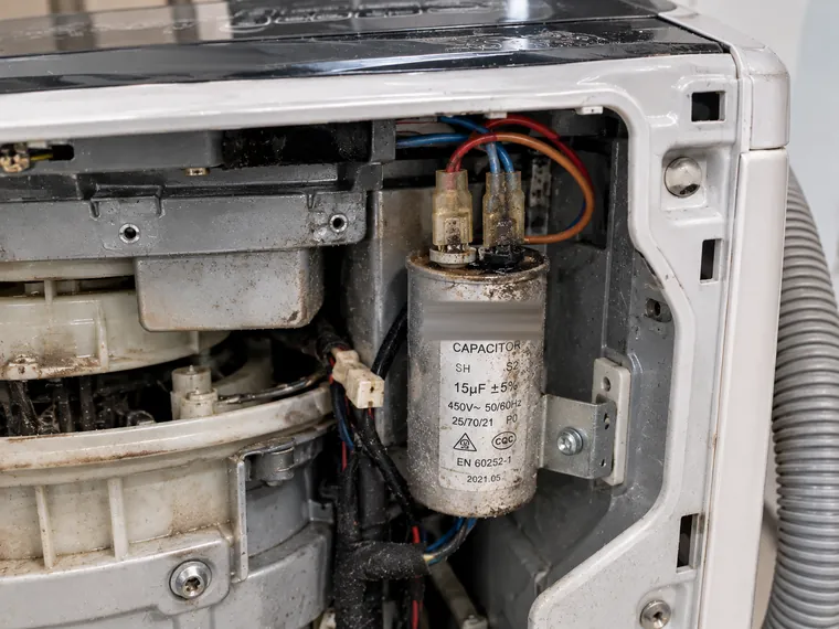 Corroded motor capacitor in a top load washing machine before replacement